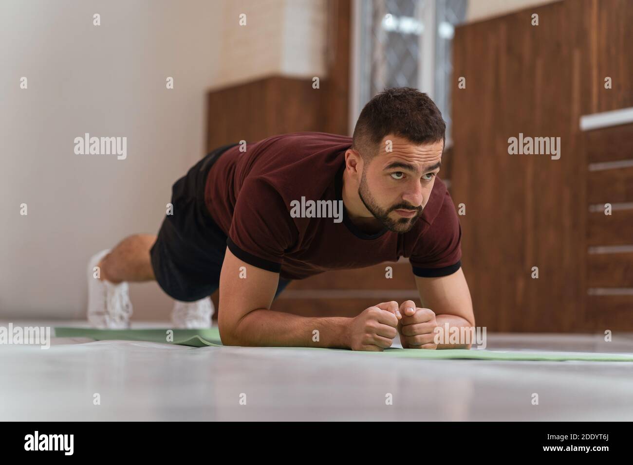 Forte bel giovane uomo che lavora fuori facendo la tavola in palestra vuota o a casa. Sportivo muscolare facendo esercizi da solo mentre auto distanza o blocco in Foto Stock