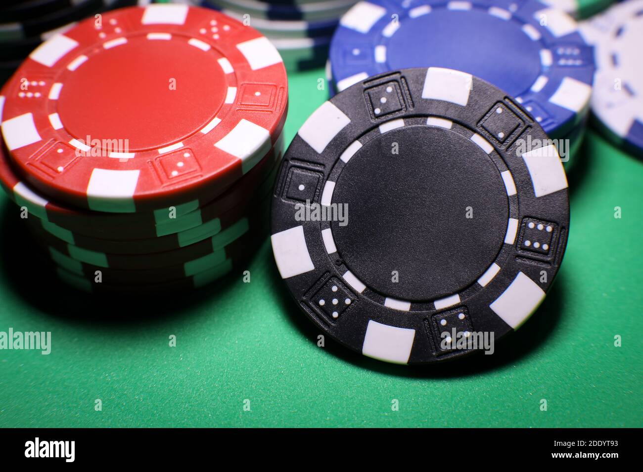 Diversi chip di gioco di poker su un tavolo verde su sfondo nero. Gioco online. . Foto di alta qualità Foto Stock