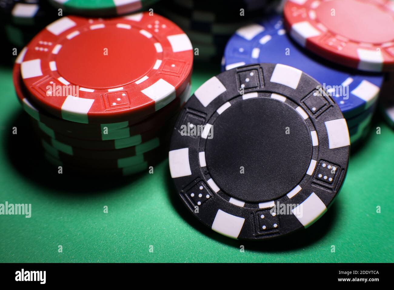 Diversi chip di gioco di poker su un tavolo verde su sfondo nero. Gioco online. . Foto di alta qualità Foto Stock