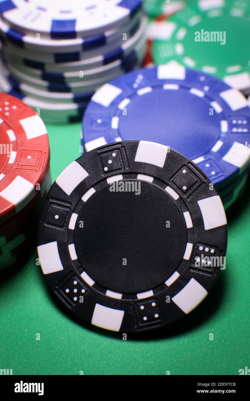 Diversi chip di gioco di poker su un tavolo verde su sfondo nero. Gioco online. . Foto di alta qualità Foto Stock