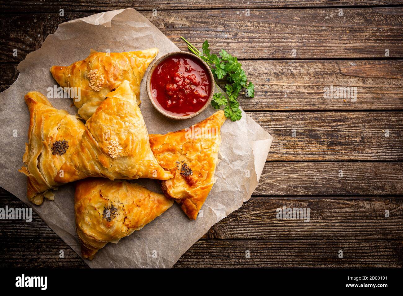 Samsa o samosa con carne e verdure con salsa di pomodoro su fondo ligneo. Cucina asiatica tradizionale. Vista dall'alto. Foto Stock