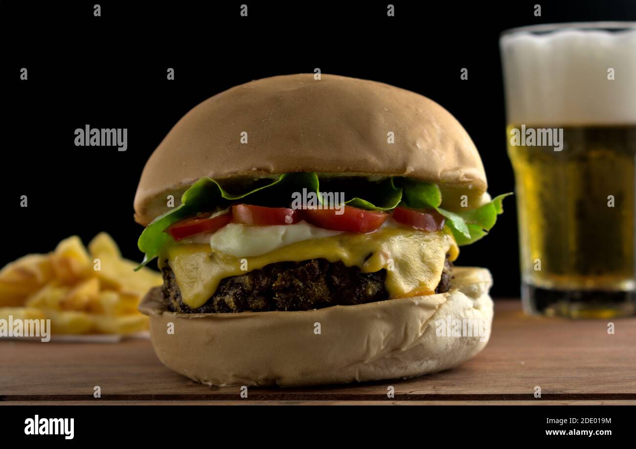 fotografia di un hamburger vegetariano con salsa di soia accompagnata da patate dolci fritte e birra feita in studio fotografico Foto Stock