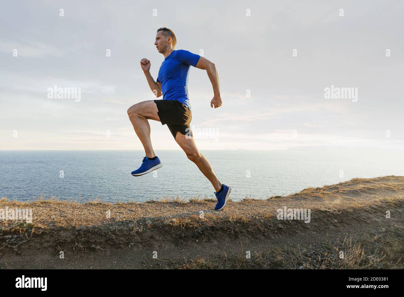 atleta uomo maturo correre su sentiero di montagna in cielo di sfondo e mare Foto Stock