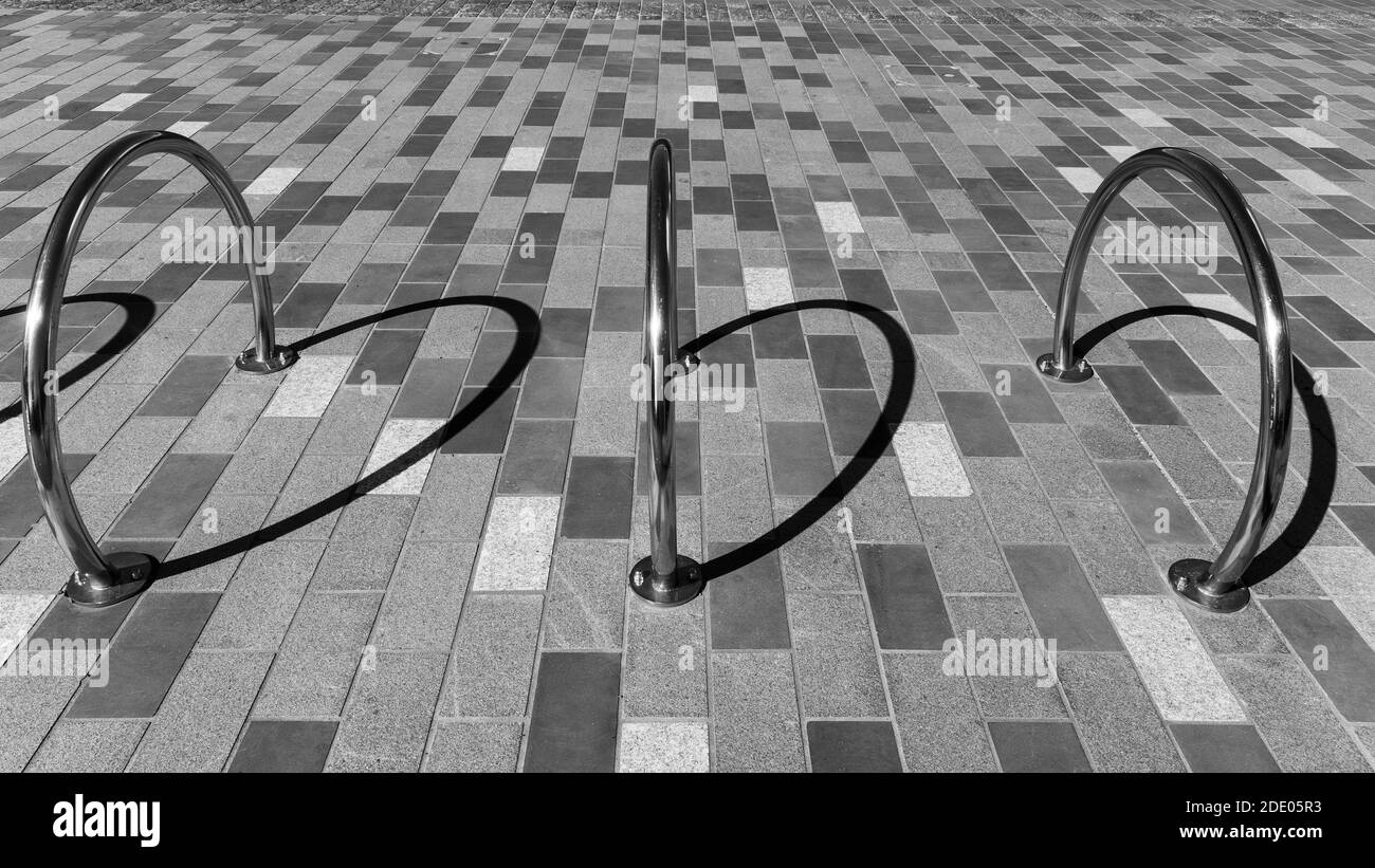 Immagine astratta dei supporti per biciclette e delle ombre sulle piastrelle da pavimento con motivo a scacchi in bianco e nero. Foto Stock