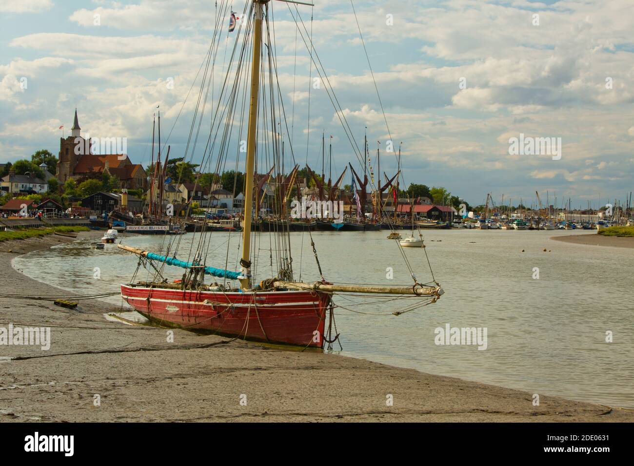 Una barca all'ancora a bassa marea a Maldon in Essex, con chiatte Tamigi sullo sfondo Foto Stock