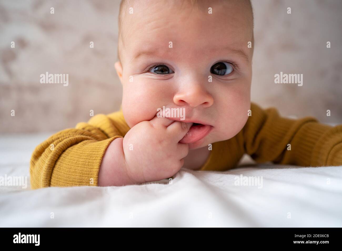 Piccolo, grazioso funny baby infant teething con espressione faccia le mani e le dita in bocca gengive infiammate lenire Foto Stock