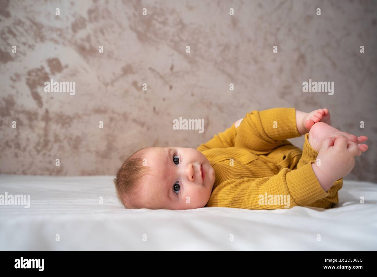 Bambino di cinque mesi. Adorabile bambino in camera soleggiata. Bambino neonato che si rilassa a letto. Asilo nido per bambini Foto Stock