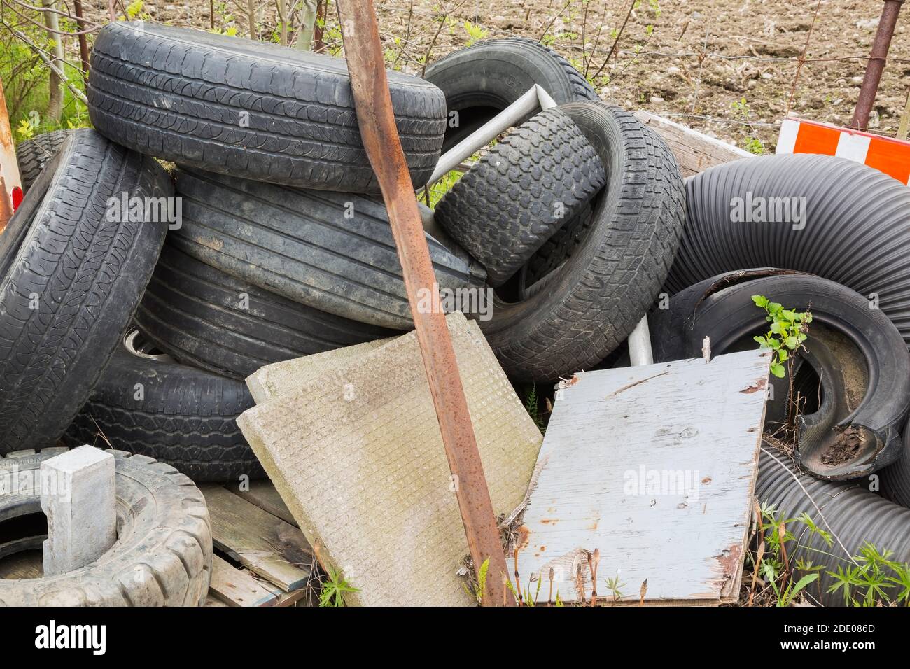 Pila di gomme nere scartate per camion, piastrelle di cemento, legno e acciaio. Foto Stock