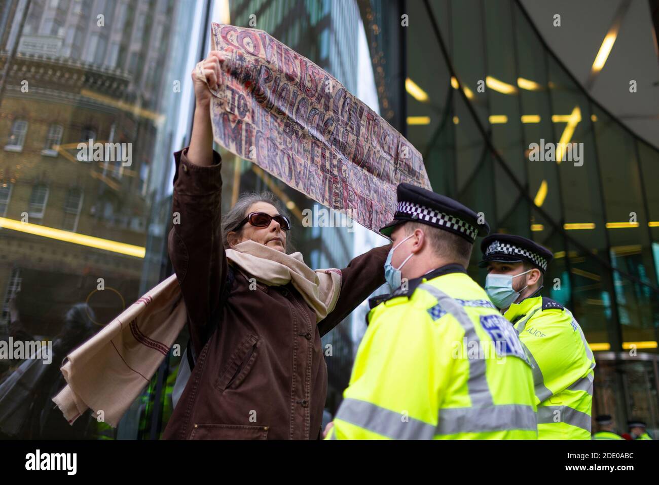 Il manifestante tiene un cartello davanti alla polizia durante la protesta contro la vaccinazione, Bill e Melinda Gates Foundation Office, Londra, 24 novembre 2020 Foto Stock