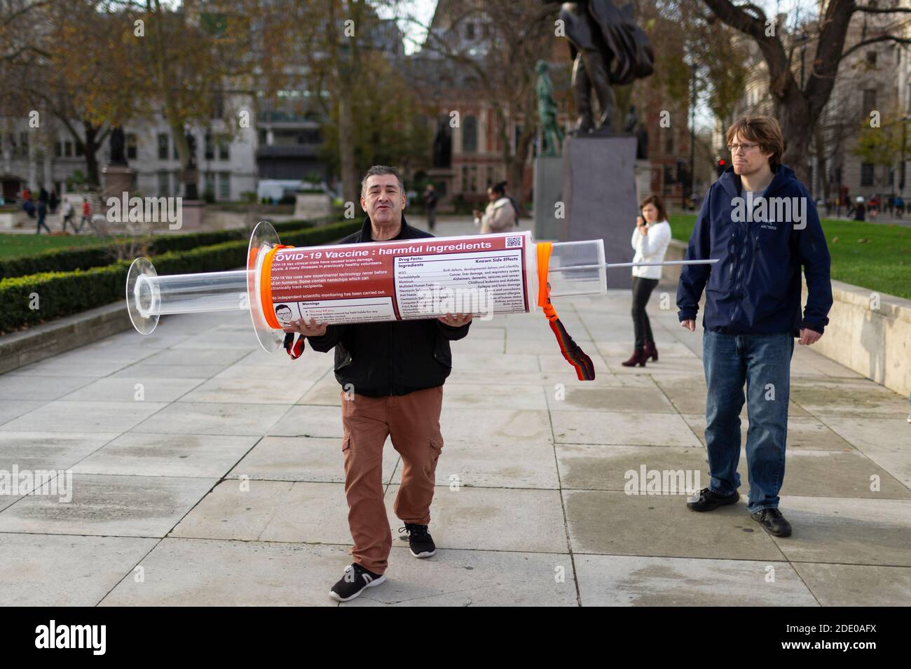 Protester che tiene una siringa gigante durante la protesta anti-vaccinazione, Parliament Square, Londra, 24 novembre 2020 Foto Stock