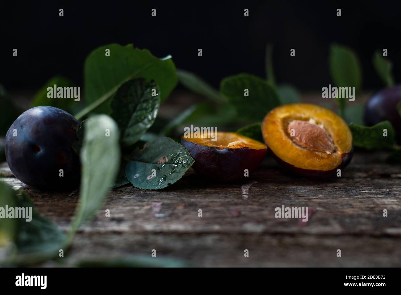 Prugne organiche fresche poste vicino alle foglie Foto Stock