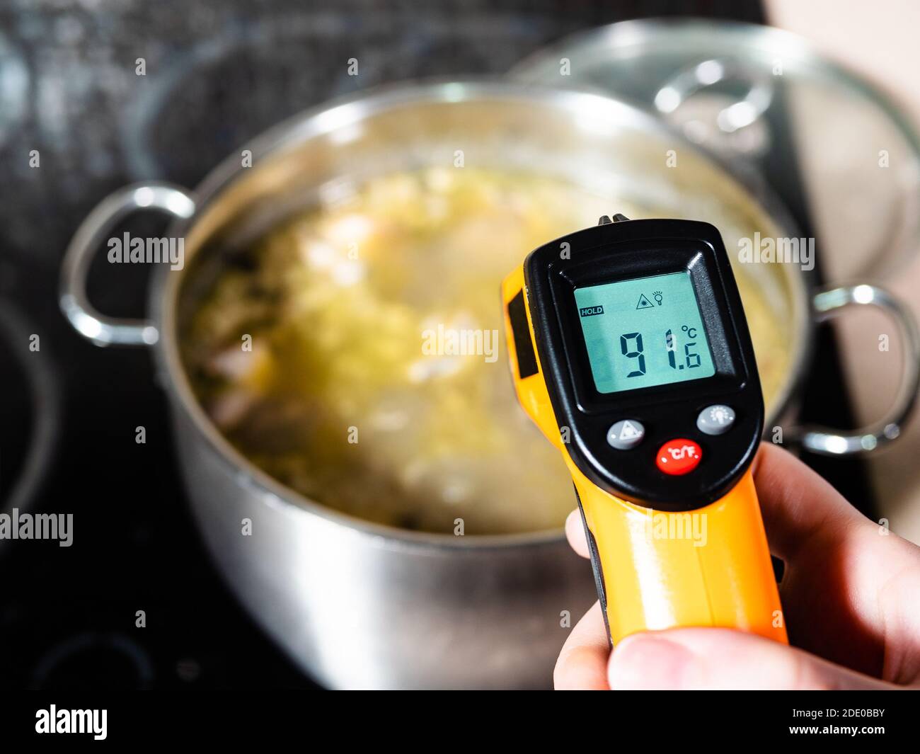misurazione della temperatura della zuppa di pesce durante la cottura in  pentola da termometro a infrarossi su stufa in ceramica a casa cucina Foto  stock - Alamy