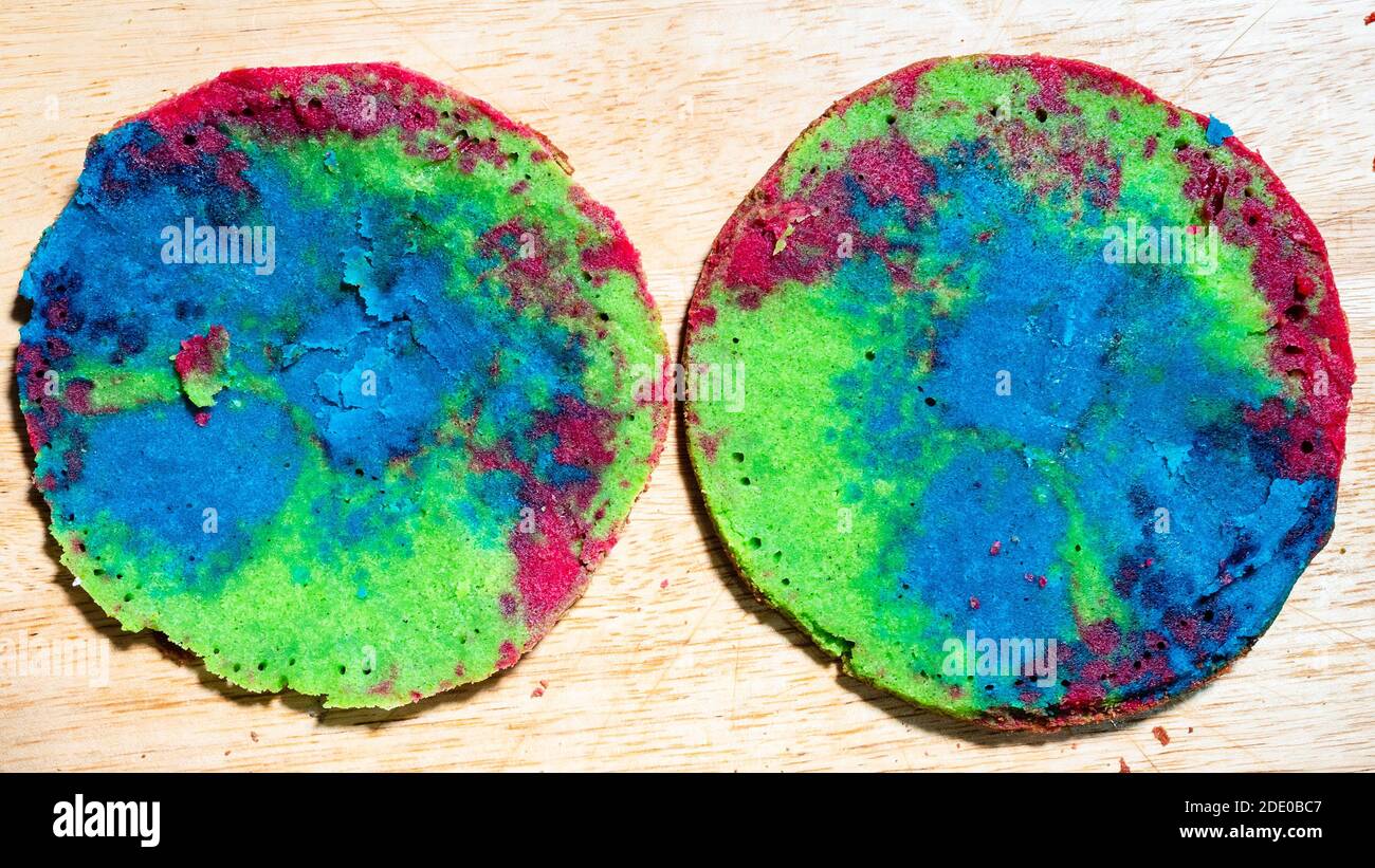 cottura dolce pan di spagna a casa - vista dall'alto di due strati colorati di torta cotta su tavola di legno cucina a casa Foto Stock