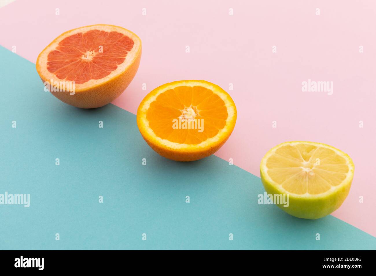 Pompelmo, arancia e limone su sfondo rosa e blu Foto Stock