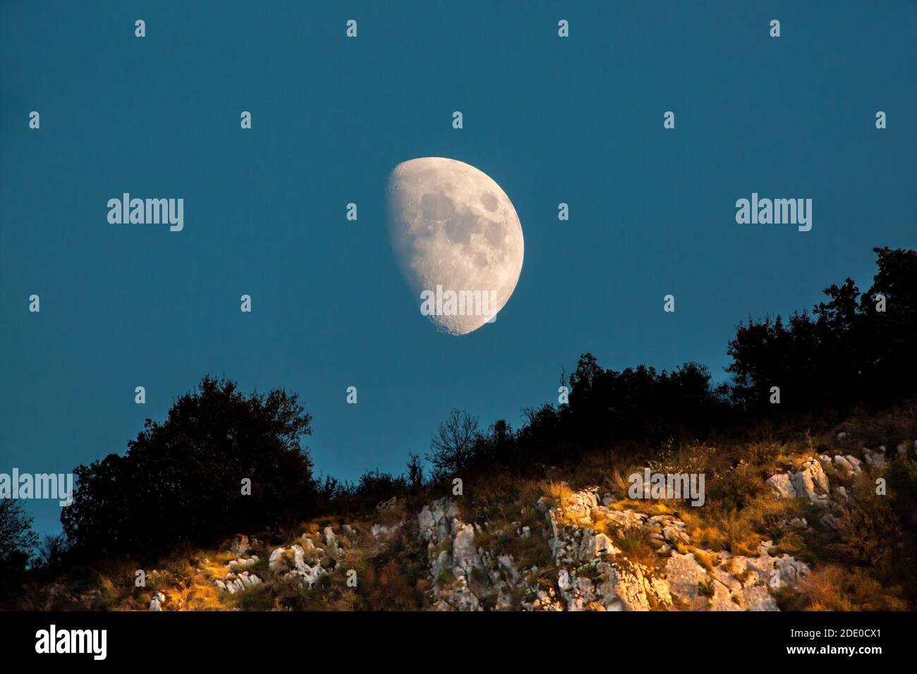Le scogliere sopra il fiume Ardeche sono striate con la luce del sole che tramonta mentre la luna sale sopra di loro. Foto Stock