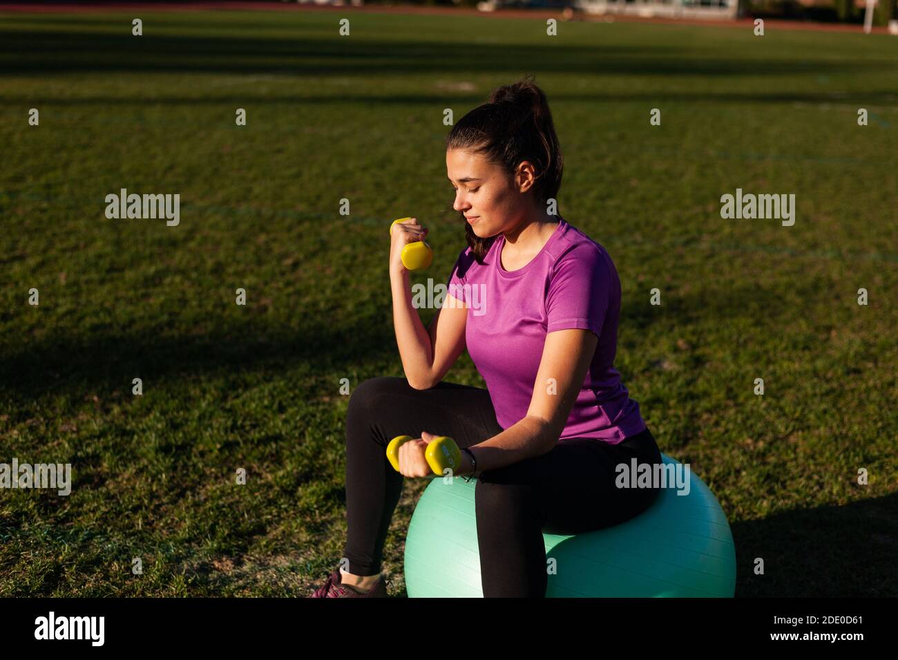 Donna seduta su fitball e facendo esercizi con manubri Foto Stock