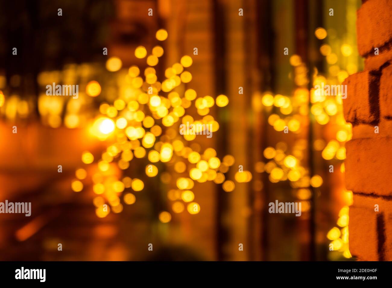 Serata accogliente nella città festosa. Immagine offuscata di vetrine decorate con ghirlande chiare per le celebrazioni di Natale e Capodanno. Finestra luminosa Foto Stock