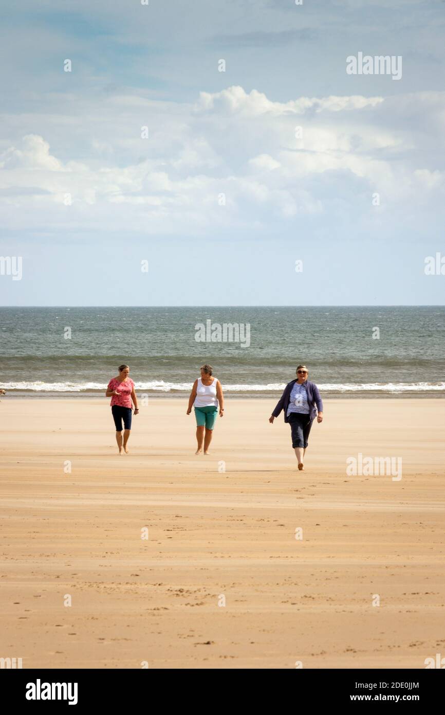 3 donne di mezza età che camminano verso la macchina fotografica a Druridge Bay spiaggia in Northumberland Foto Stock