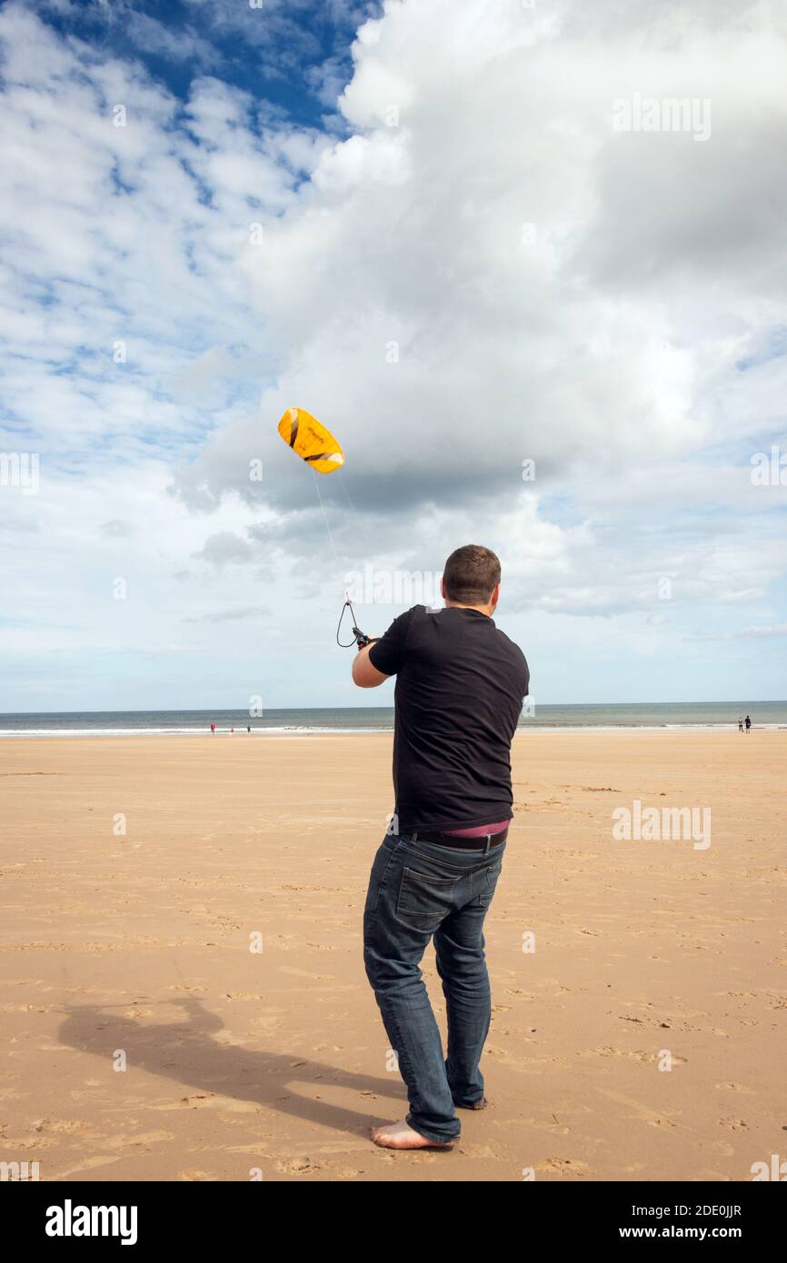 Il giovane uomo kite surf sulla spiaggia di Druridge Bay in Northumberland Foto Stock