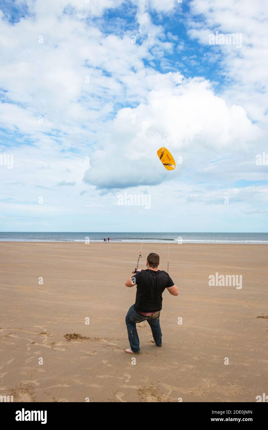 Il giovane uomo kite surf sulla spiaggia di Druridge Bay in Northumberland Foto Stock