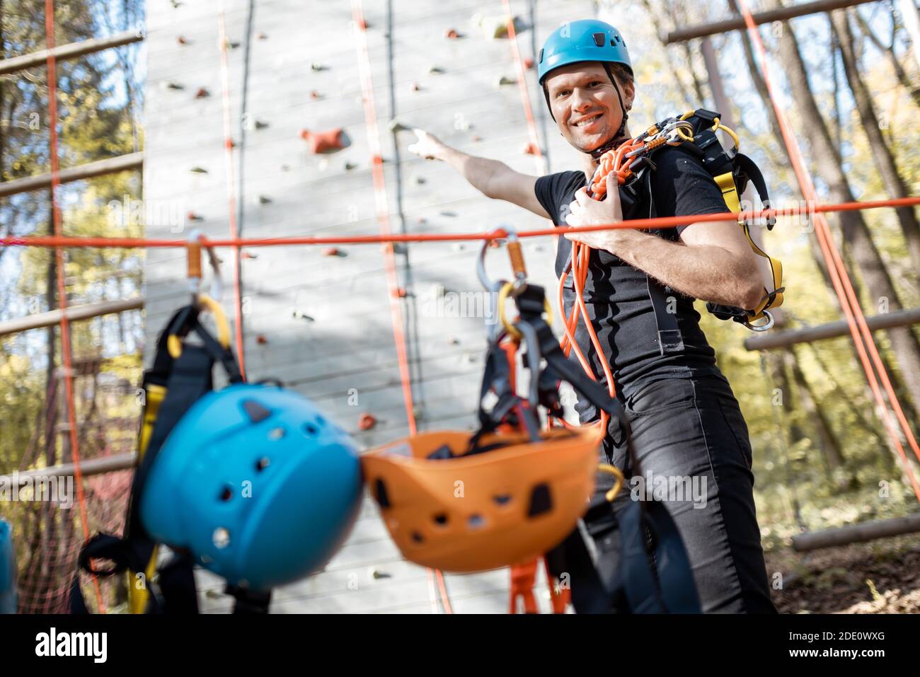 Ritratto di un uomo felice ben attrezzato con arrampicata protettiva attrezzature al parco divertimenti all'aperto Foto Stock