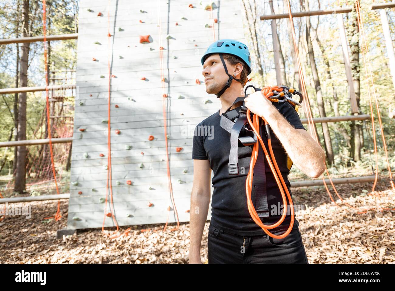 Bell'uomo ben equipaggiato con attrezzatura protettiva per l'arrampicata in piedi parco divertimenti all'aperto Foto Stock