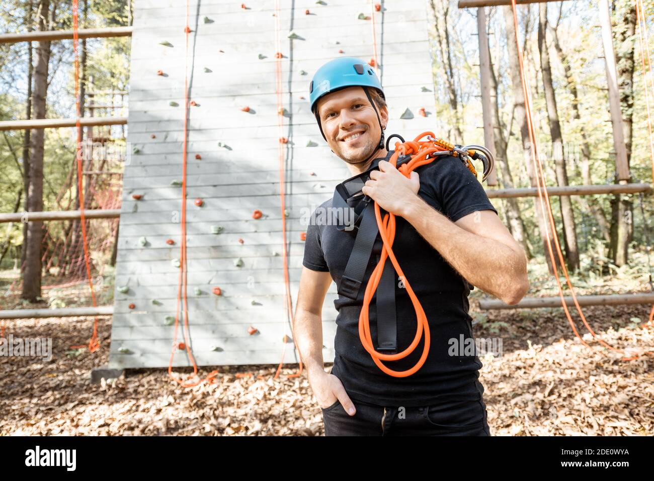 Ritratto di un uomo felice ben attrezzato con arrampicata protettiva attrezzature al parco divertimenti all'aperto Foto Stock