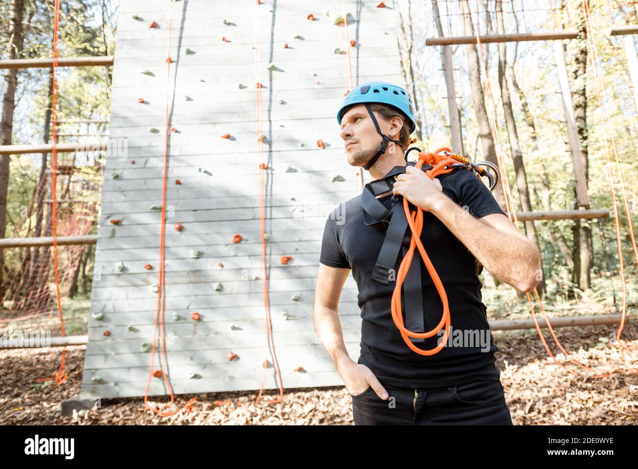 Ritratto di un uomo felice ben attrezzato con arrampicata protettiva attrezzature al parco divertimenti all'aperto Foto Stock