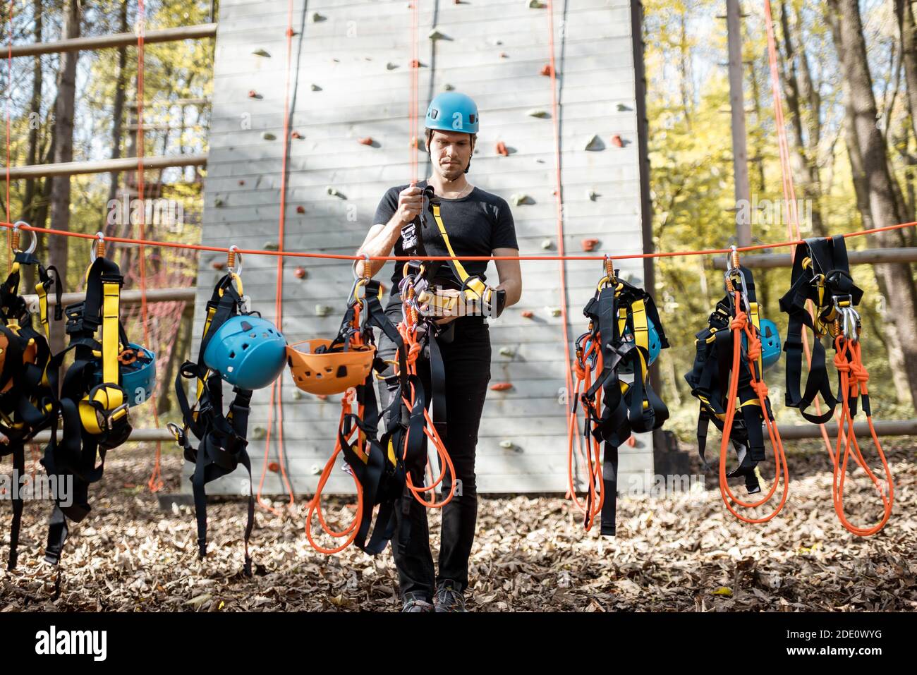 Bell'uomo che indossa attrezzature di sicurezza per l'arrampicata al parco divertimenti, preparandosi per l'arrampicata sulla parete Foto Stock