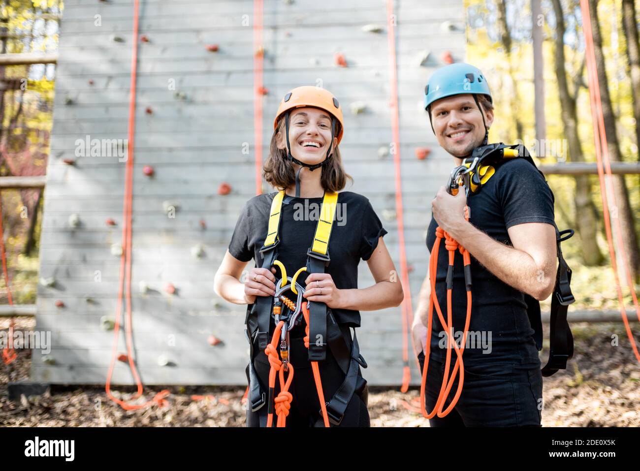 Ritratto di una giovane coppia ben attrezzata con equipaggiamento di sicurezza stare insieme di fronte alla parete di arrampicata al divertimento parcheggio Foto Stock