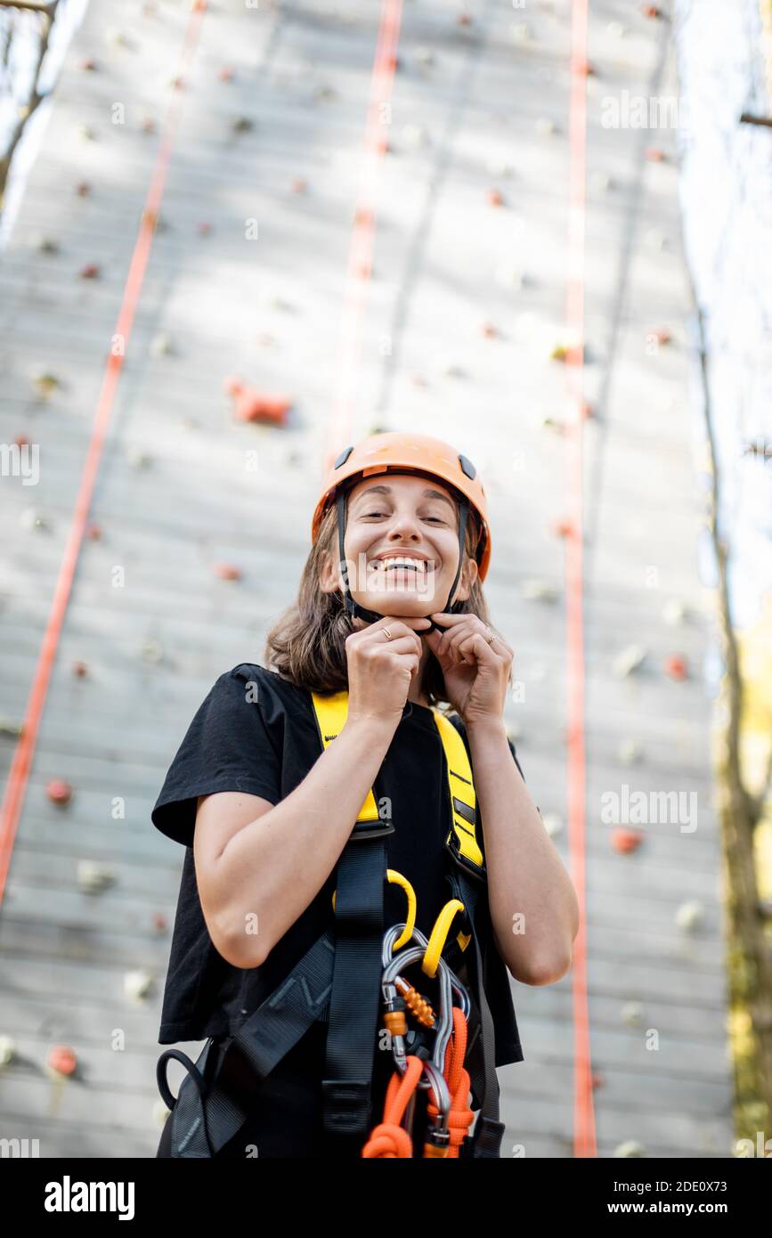 Ritratto di una giovane donna ben attrezzata in piedi davanti della parete di arrampicata al parco divertimenti Foto Stock