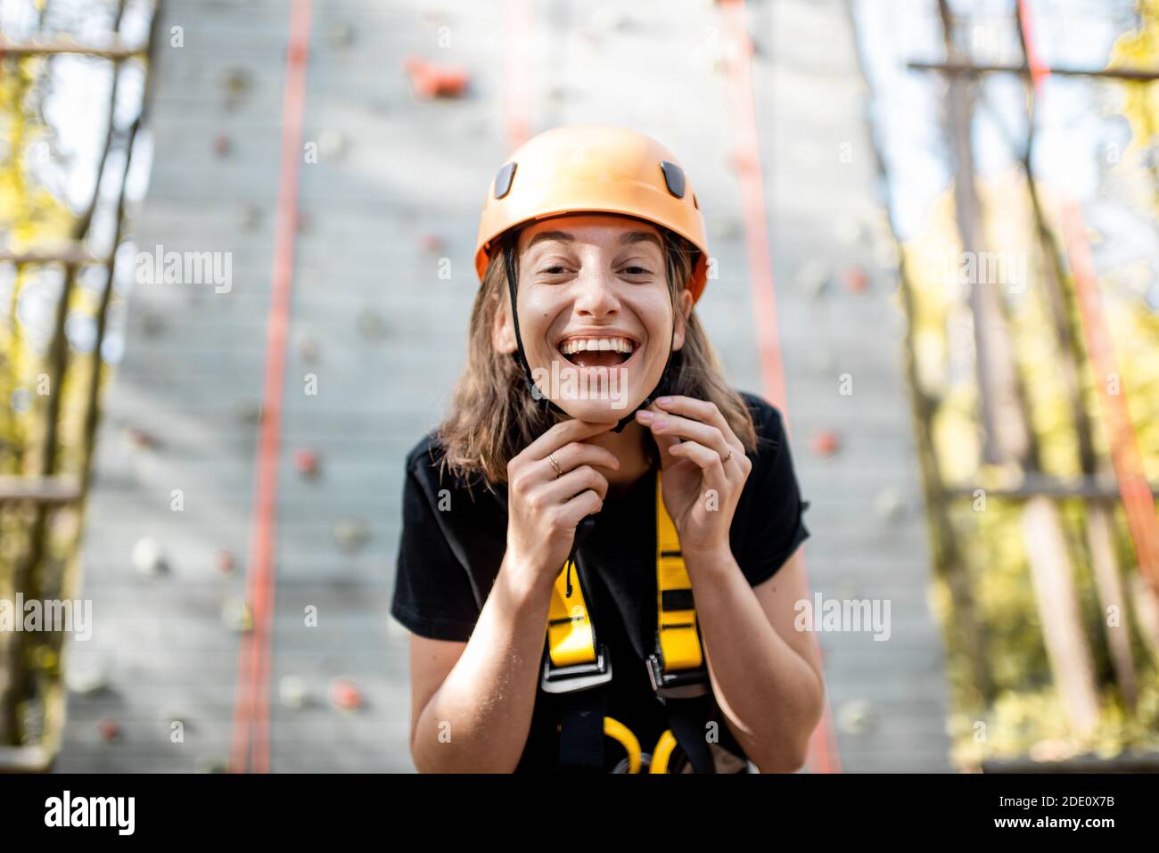 Ritratto di una giovane donna ben attrezzata in piedi davanti della parete di arrampicata al parco divertimenti Foto Stock