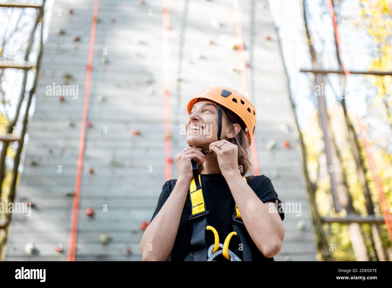 Ritratto di una giovane donna ben attrezzata in piedi davanti della parete di arrampicata al parco divertimenti Foto Stock