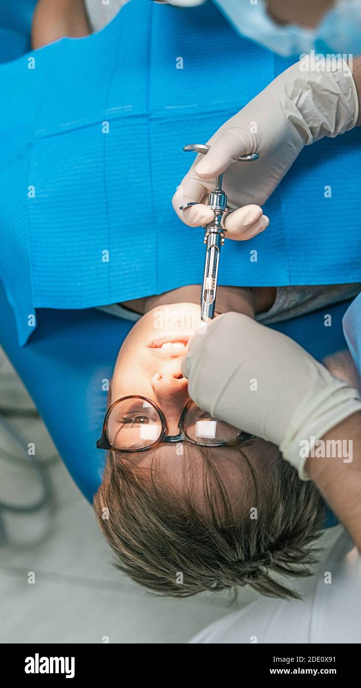 Foto di scorta di un assistente dentistico non riconosciuto che utilizza l'ago per porre l'anestesia al paziente giovane. Foto Stock