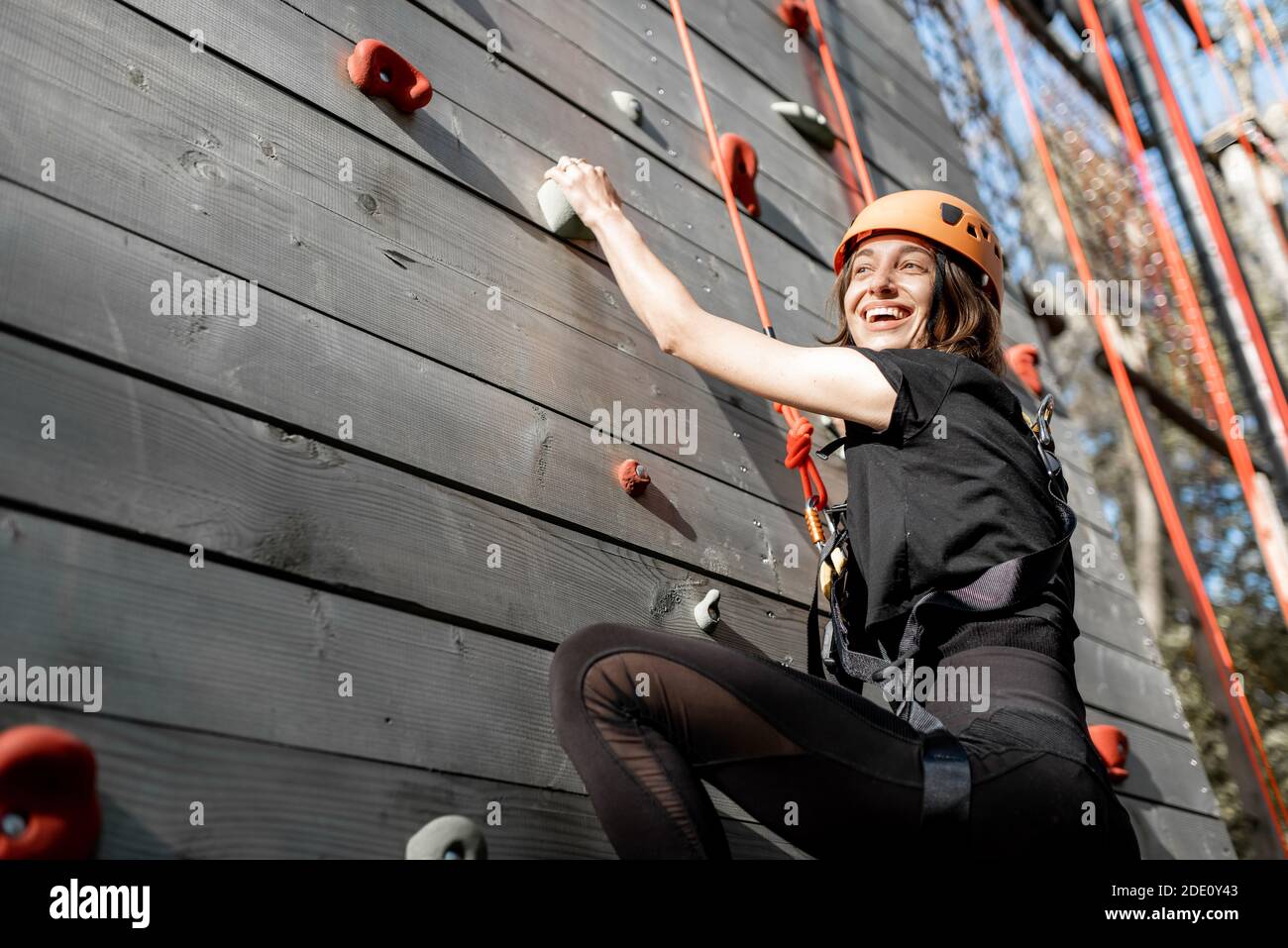 Giovane donna ben attrezzata che sale la parete all'aperto nel parco per l'intrattenimento sportivo Foto Stock