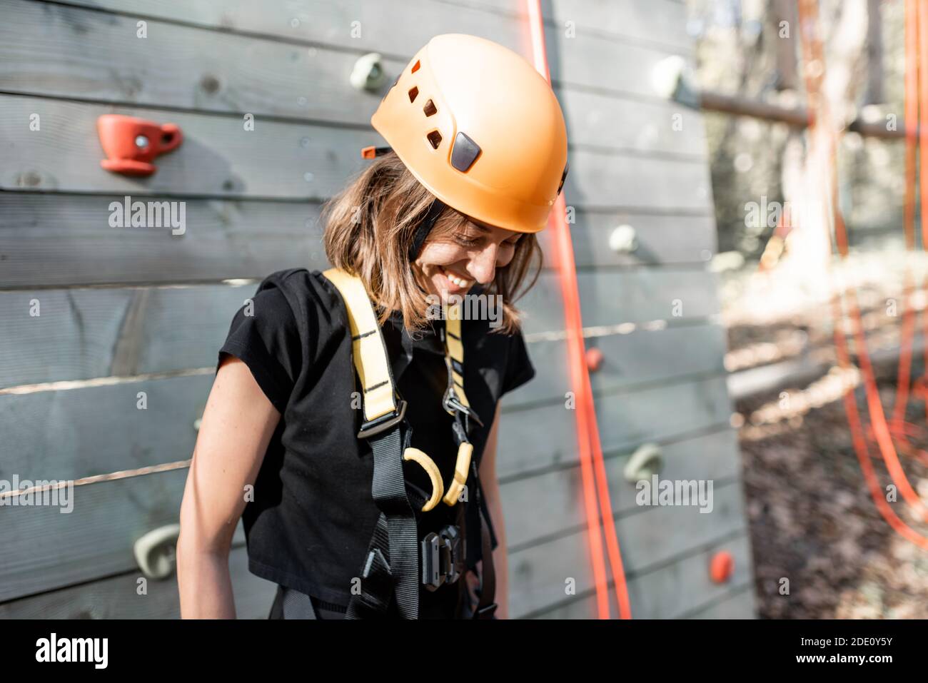 Ritratto di una giovane donna felice in attrezzature sportive vicino la parete di arrampicata nel parco per l'intrattenimento sportivo Foto Stock