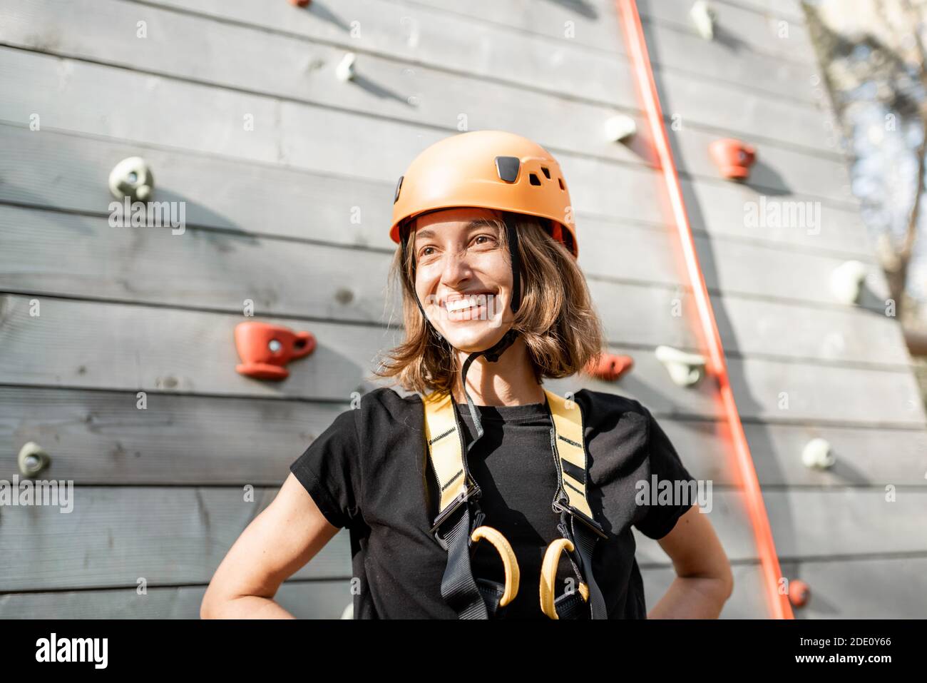 Ritratto di una giovane donna felice in attrezzature sportive vicino la parete di arrampicata nel parco per l'intrattenimento sportivo Foto Stock