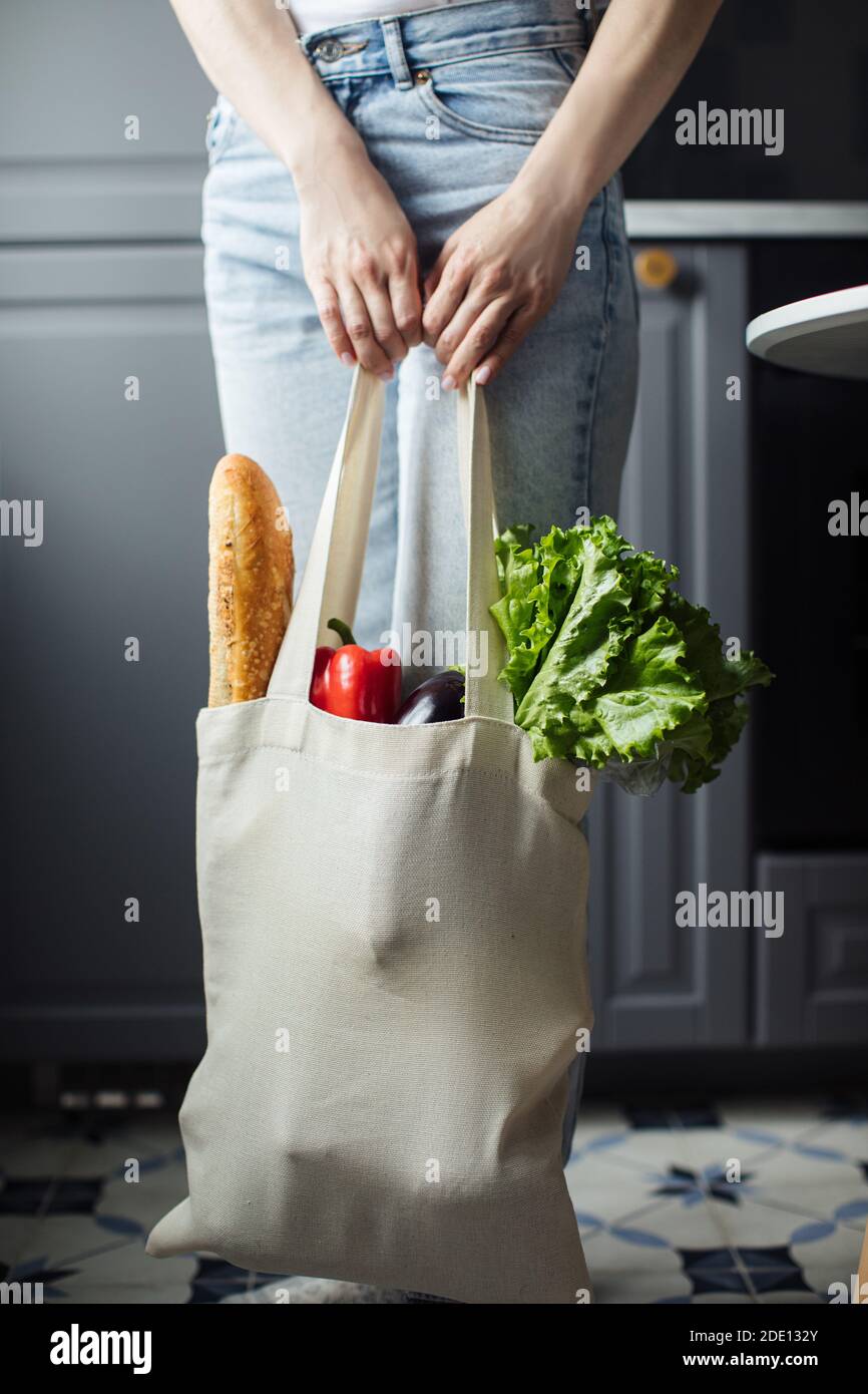 Mano femminile con eco bag su sfondo grigio Foto Stock