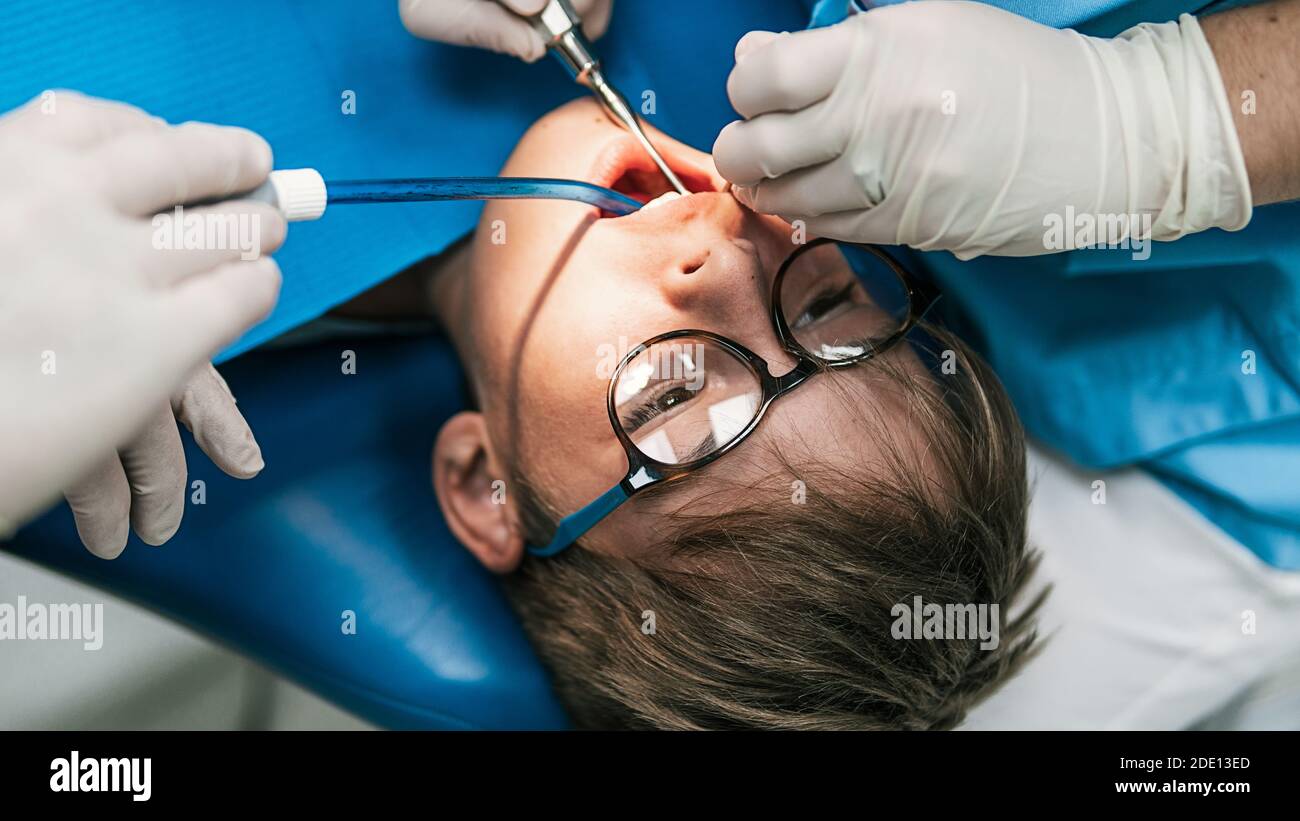 Foto d'inventario del ragazzo carino durante la revisione presso il dentista. Ha la bocca aperta. Foto Stock