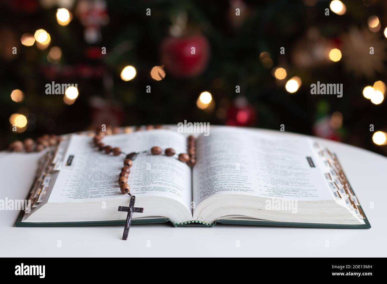 Apri la bibbia con i perline di preghiera rosario in legno che si stendano a pagina Con albero di Natale in background Foto Stock