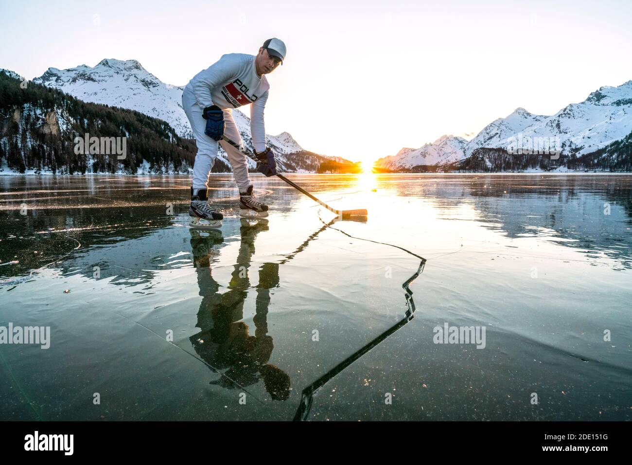 Vista frontale del giocatore di hockey su ghiaccio sulla superficie incrinata del lago ghiacciato Sils, Engadina, Cantone Graubunden, Svizzera, Europa Foto Stock