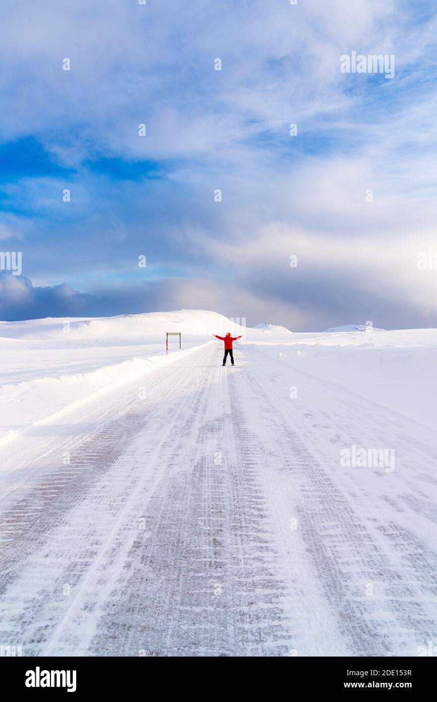 Uomo felice con le armi sollevate in piedi sulla strada ghiacciata nevosa verso Nordkapp (Capo Nord), Troms og Finnmark, Norvegia del Nord, Scandinavia, Europa Foto Stock