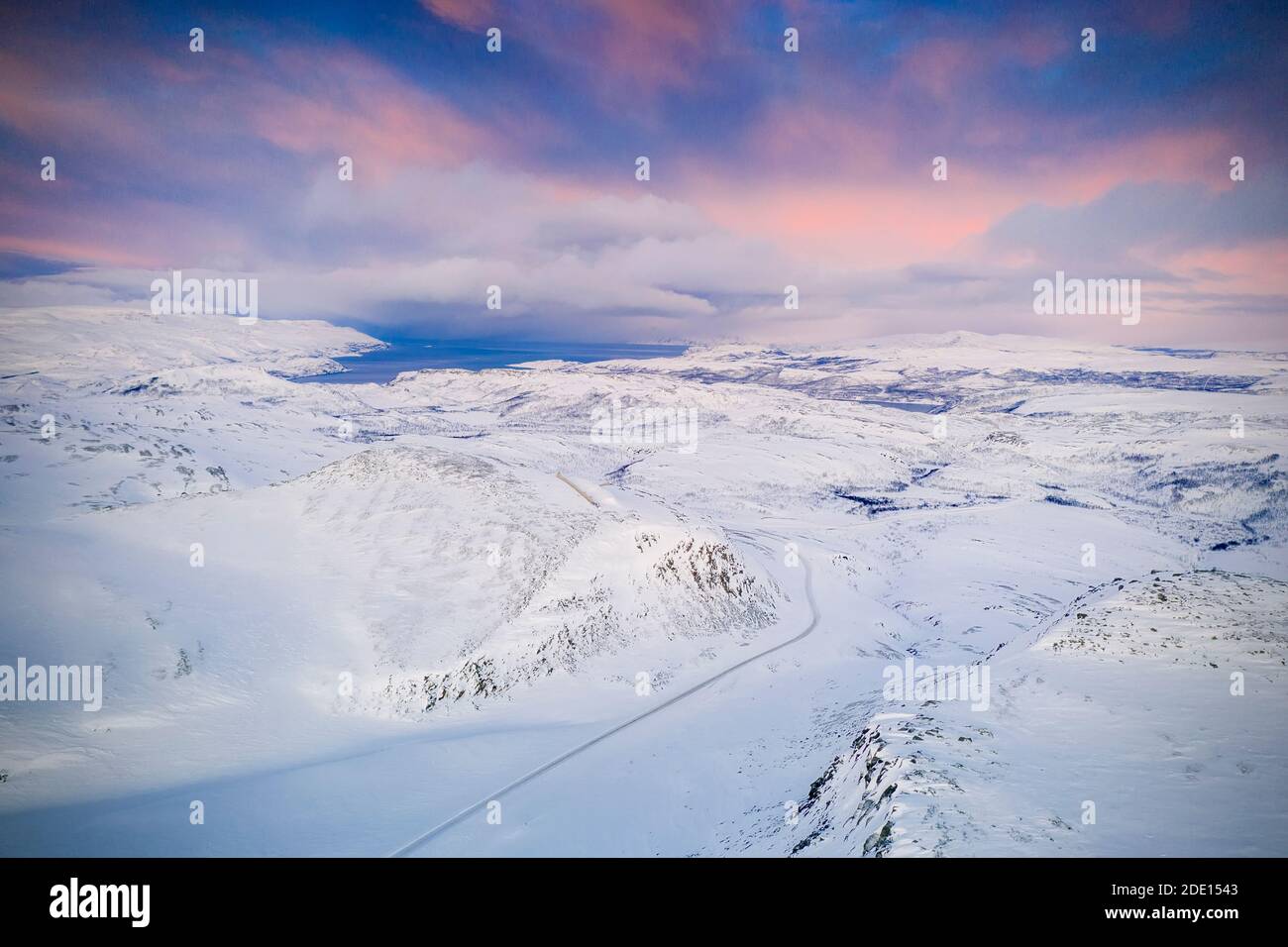 Cielo rosa all'alba su Tanafjordveien strada attraversando le montagne innevate, Tana, Troms og Finnmark, Artico, Norvegia settentrionale Foto Stock
