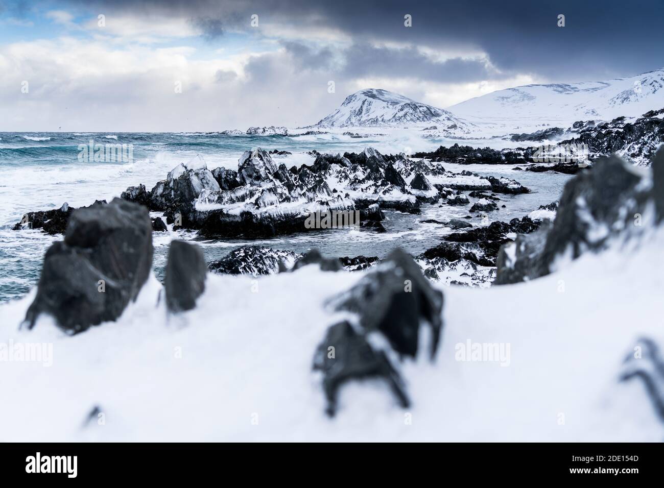 Scogliere coperte di neve sulla costa del freddo Barents Sea, Sandfjorden, Oceano Artico, Penisola di Varanger, Finnmark, Norvegia, Scandinavia, Europa Foto Stock