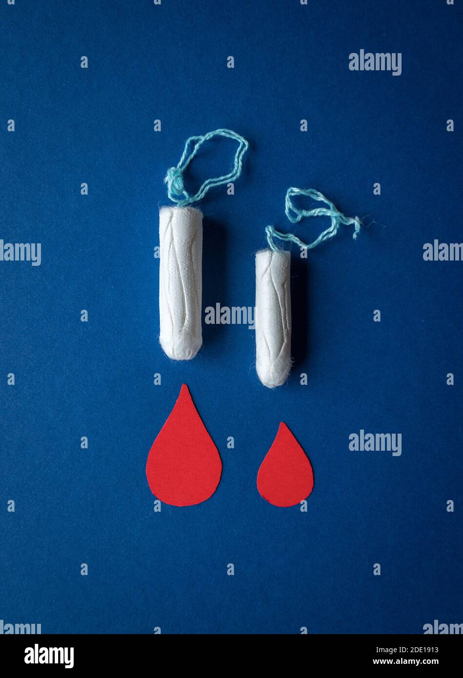 Ciclo mestruale femminile / prodotti del periodo, un tampone e assorbente igienico isolato su sfondo blu Foto Stock