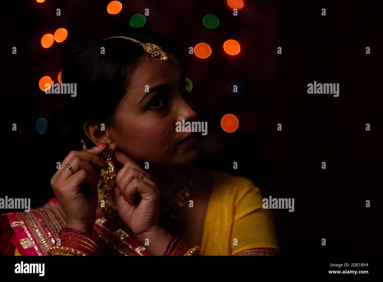 Ritratto di una bella donna bruna indiana bengalese di fronte al colorato sfondo chiaro bokeh la sera di Diwali. Stile di vita indiano Foto Stock