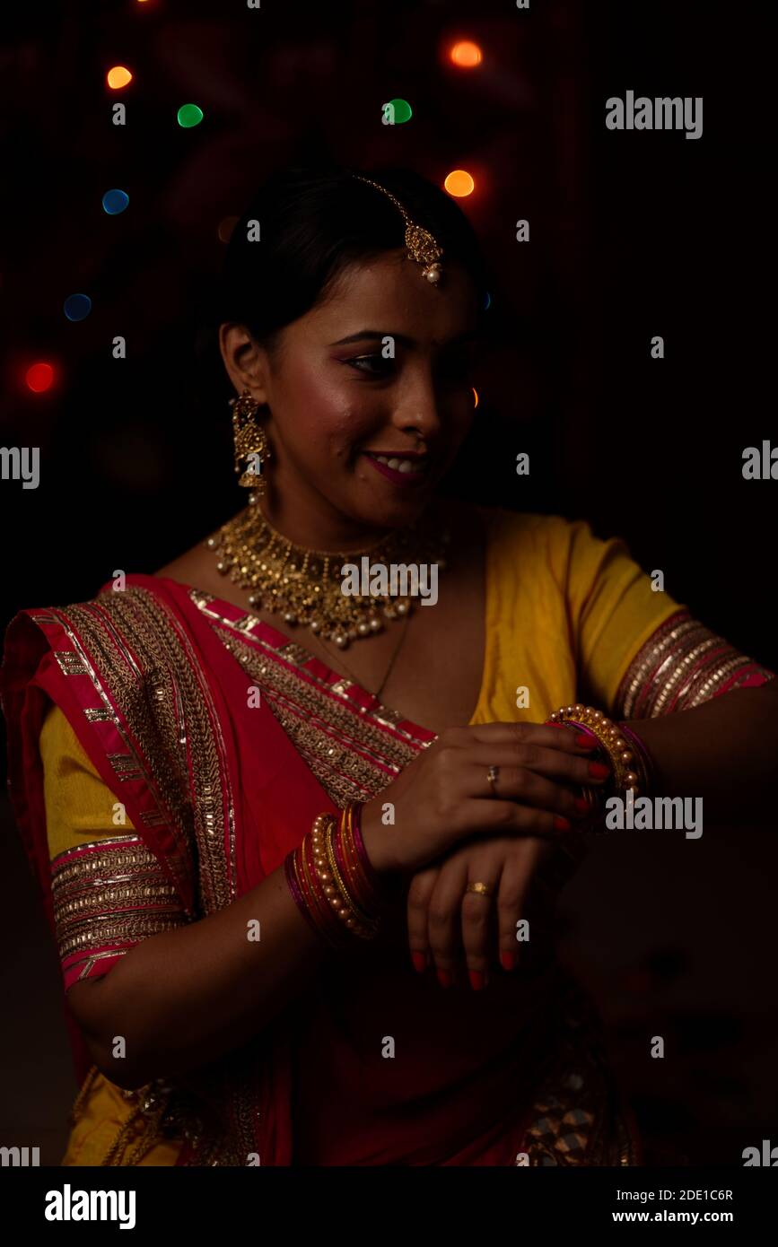 Una giovane e bella donna Bengalese indiana che celebra Diwali in abito tradizionale indiano di fronte a colorate luci bokeh. Stile di vita indiano Foto Stock