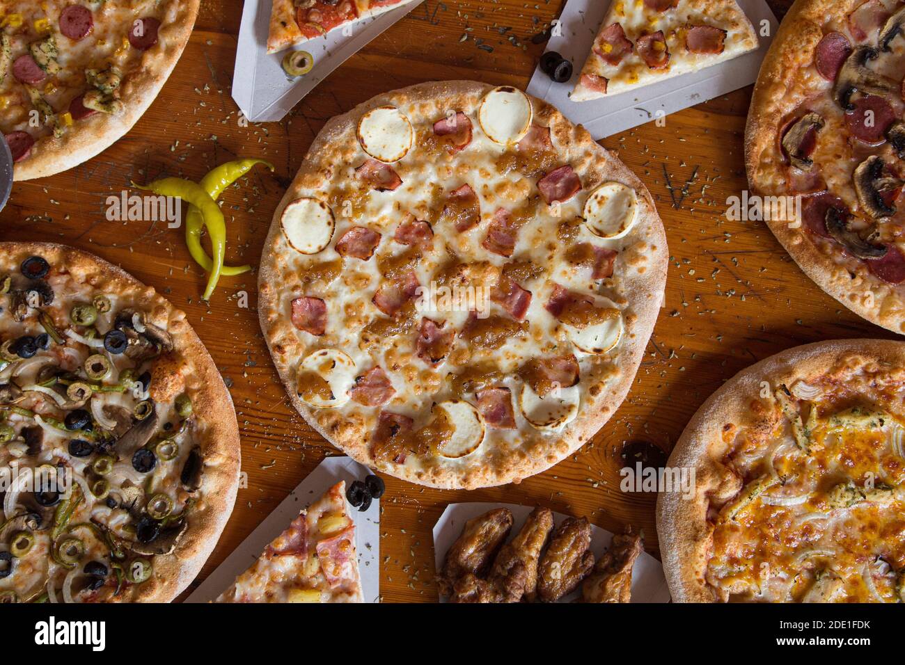 Cena a base di pizza. Piatto di vari tipi di pizza italiana su rustico tavolo in legno, vista dall'alto. Pranzo veloce, celebrazione, concetto di riunione. Foto Stock