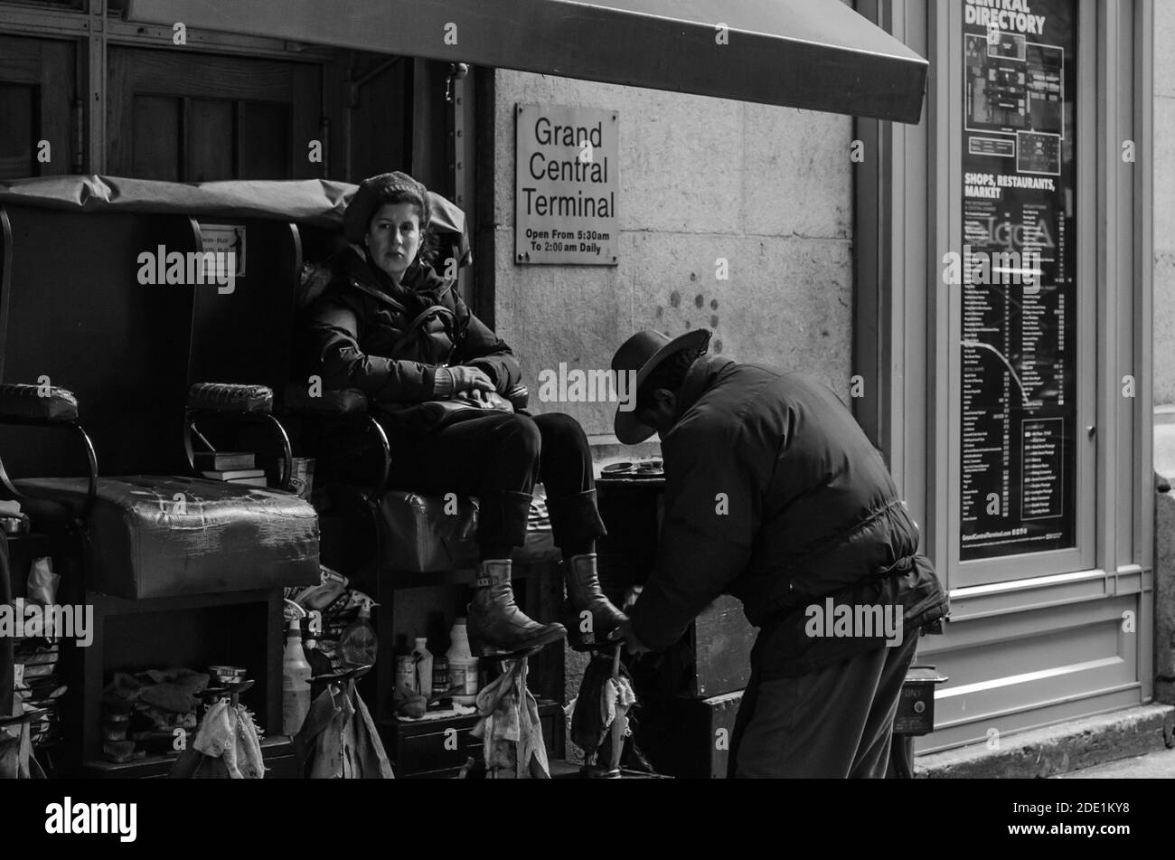 Sitting Woman ama lucidare le scarpe da un lucidatore di scarpe di Medioevo alla Grand Terminal Station. Fotografia in bianco e nero. Manhattan, New York Foto Stock