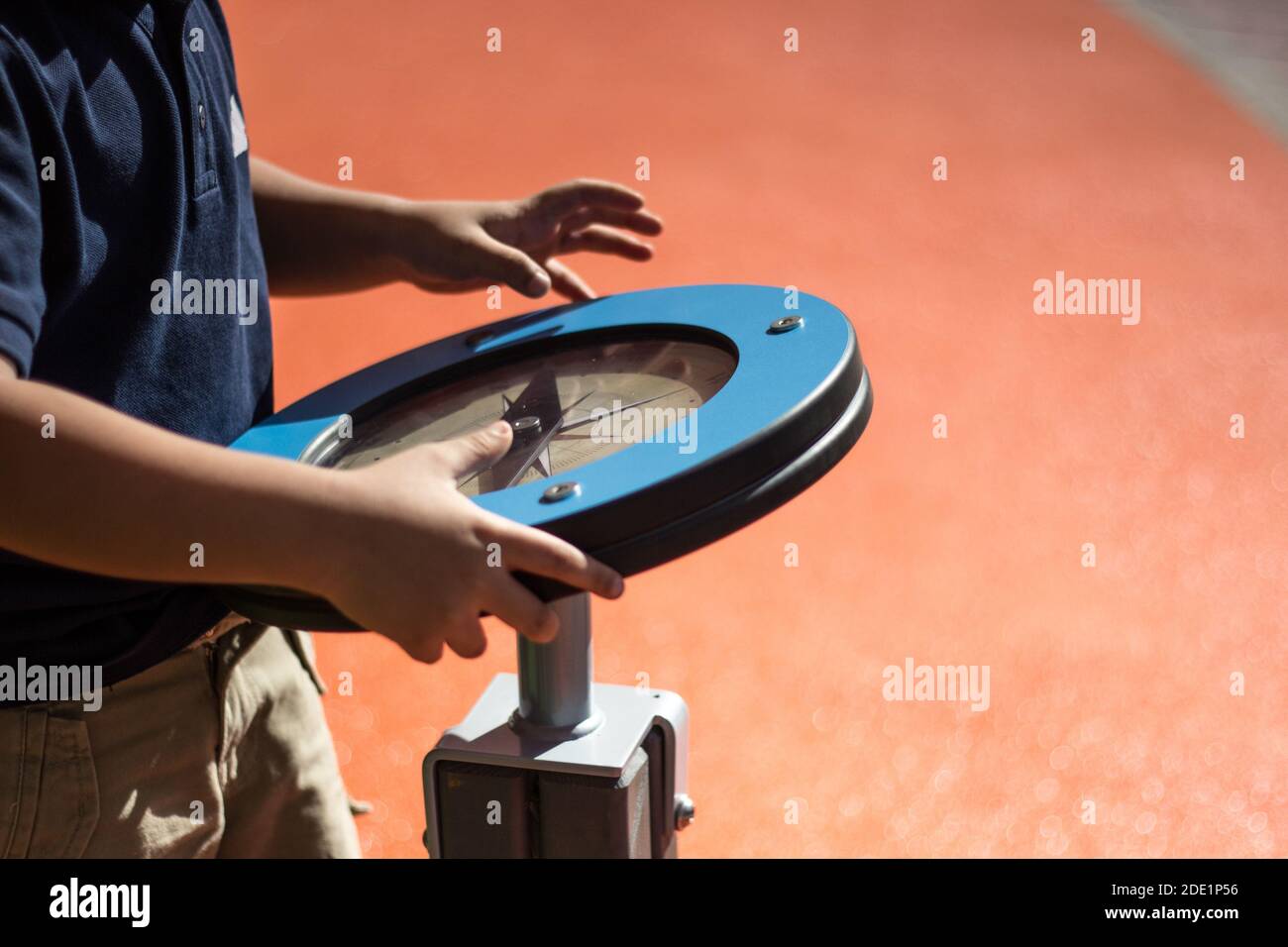 Il ragazzo ruota la ruota di gioco che è in realtà una bussola e attraverso il gioco di capretto sta imparando come usare la bussola Presso il parco giochi pubblico di Abu Dhabi Foto Stock